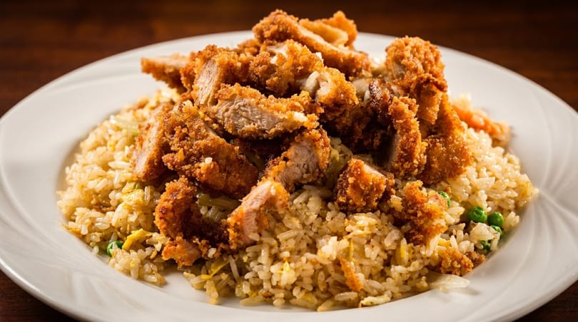 Crispy fried chicken pieces served over a bed of golden fried rice with peas and egg.